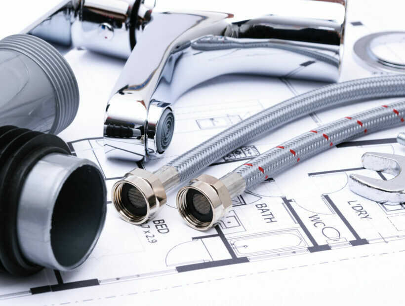 Plumbing tools and faucet on a blueprint project in close-up